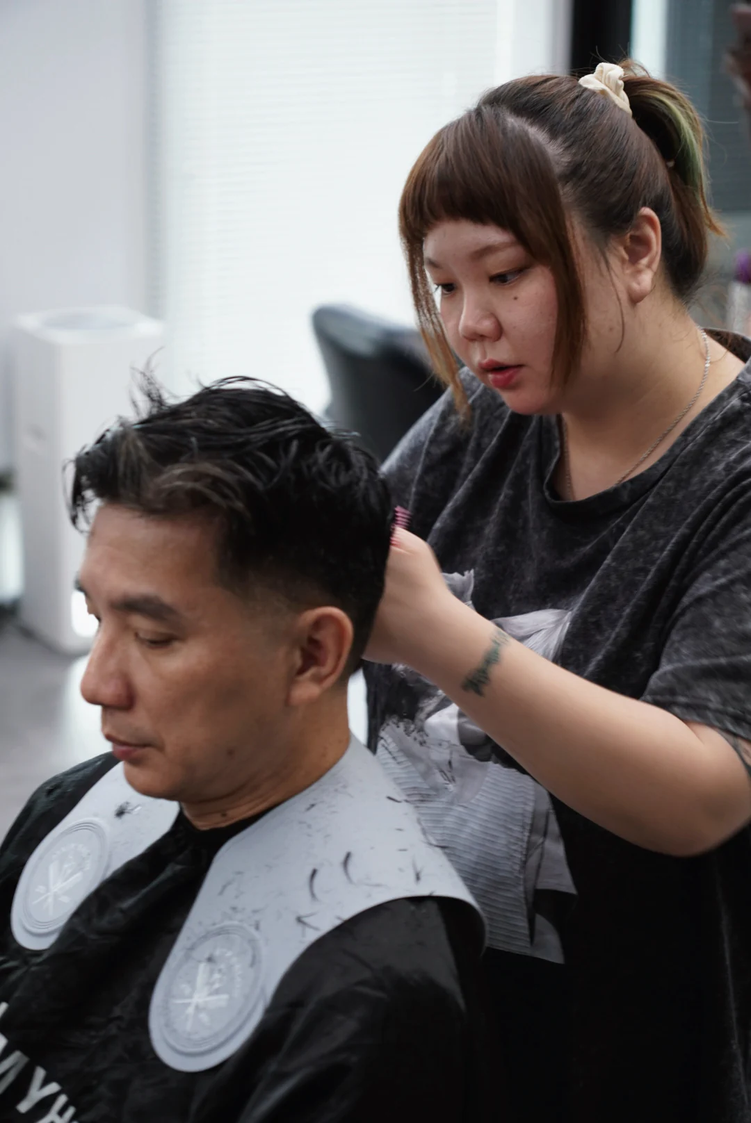 A designer and client attending to the hairstyle in front of a mirror