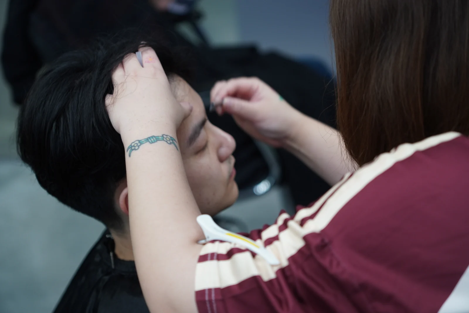 A designer arranging hair around a client's forehead